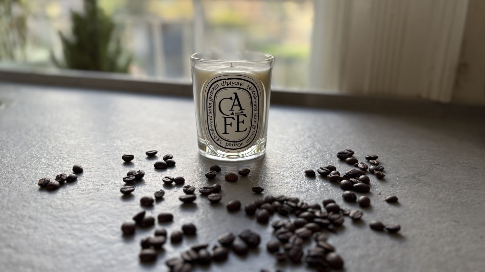 The coffee Diptyque candle with coffee beans around it