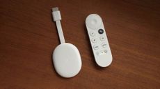 Chromecast with Google TV dongle next to remote 