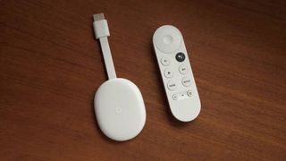 Chromecast with Google TV dongle next to remote 
