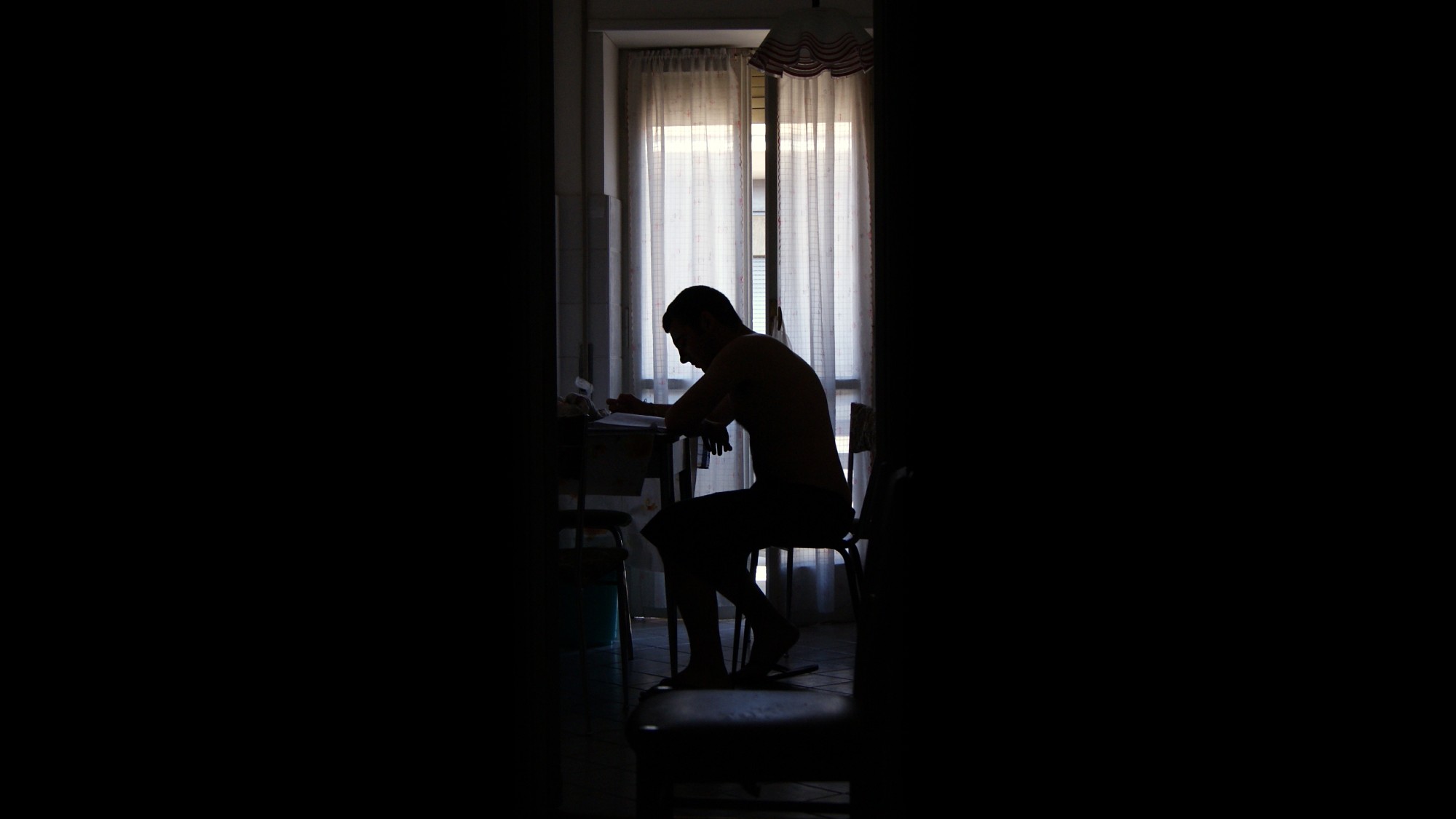 Silhouette of young man sitting at a desk in the dark