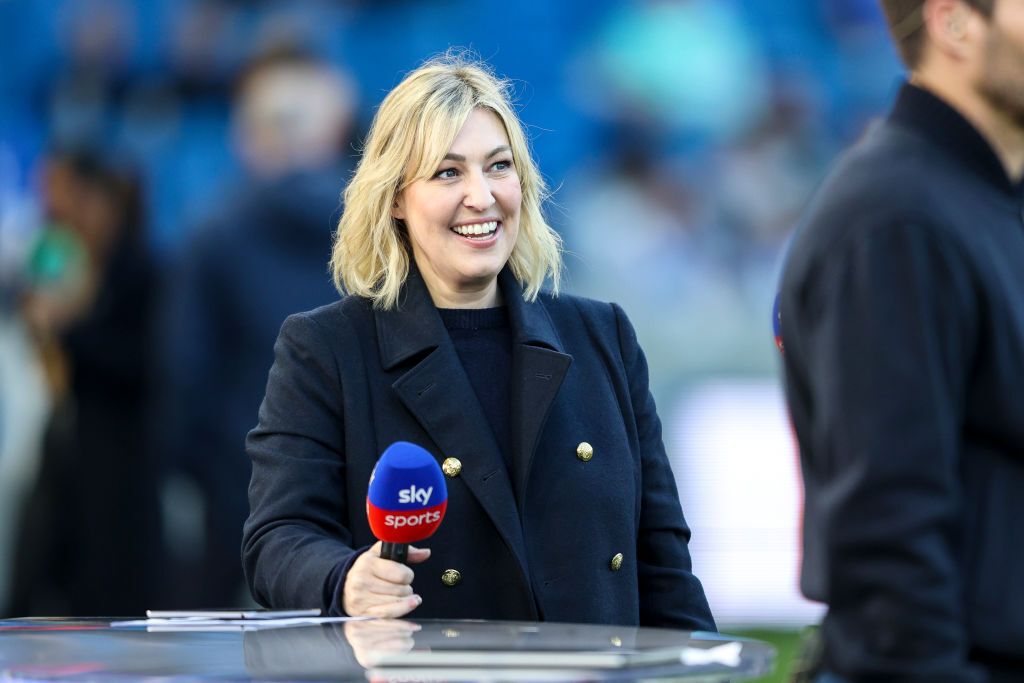 Kelly Cates at a pitchside desk holding a Sky Sports microphone