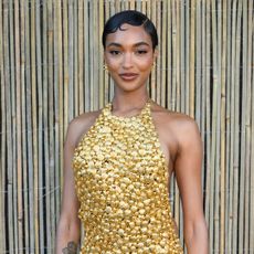 Jourdan Dunn wearing a pixie hairstyle and a gild halter neck dress.