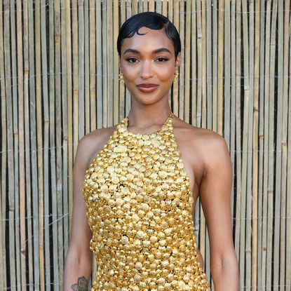 Jourdan Dunn wearing a pixie hairstyle and a gild halter neck dress. 
