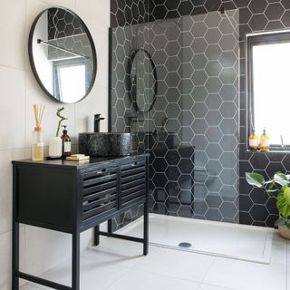 monochrome bathroom with a black tiled wall shower cubicle and marble basin