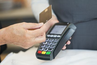 Person's hand holding a credit card to a card reader
