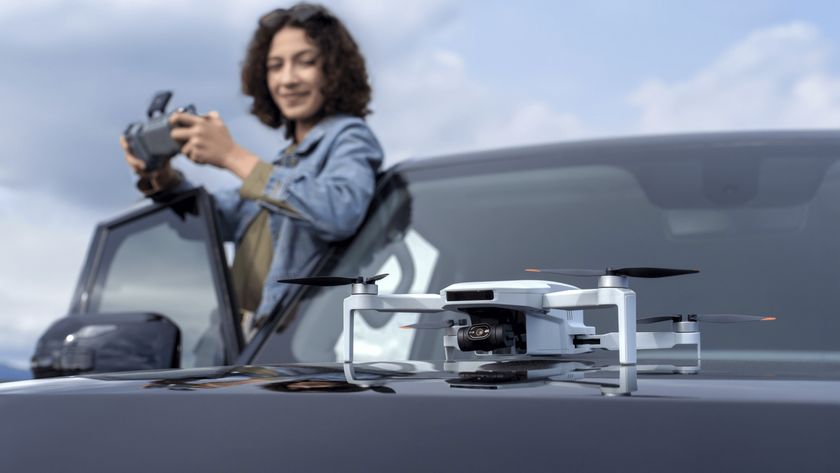 Potensic Atom 2 drone on a car bonnet, with user in background holding controller ready for takeoff