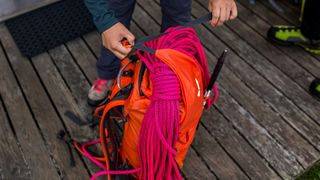 A pair of hands tightens the closure on the top of a Salewa Ortles Wall 38L Backpack.