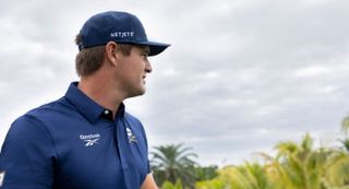 Bryson DeChambeau poses in a Reebok top