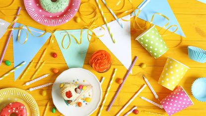 Party plates, cups and bunting on yellow table