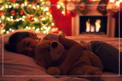 A young girl asleep in front of a Christmas tree