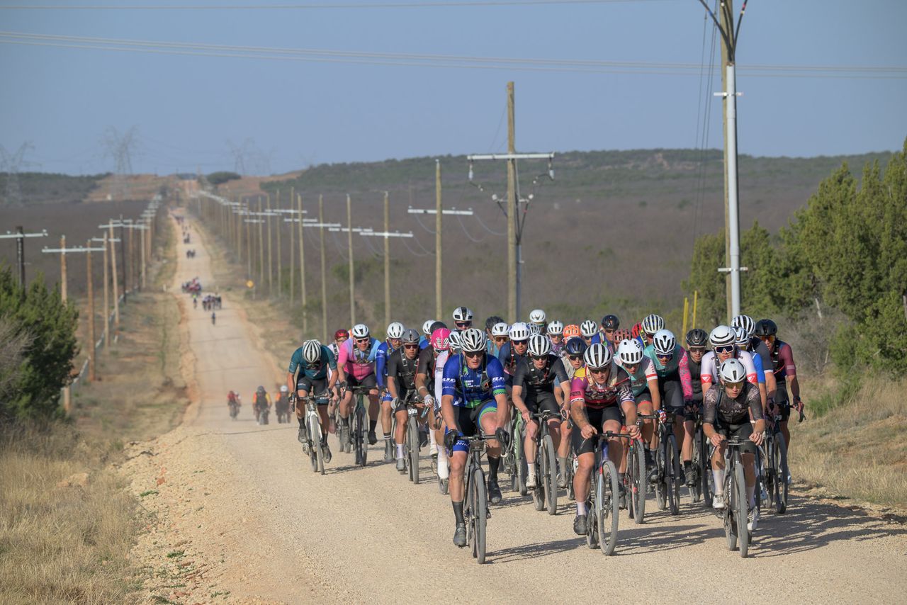 The mass start of riders crosses long stretches of rough, rocky roads