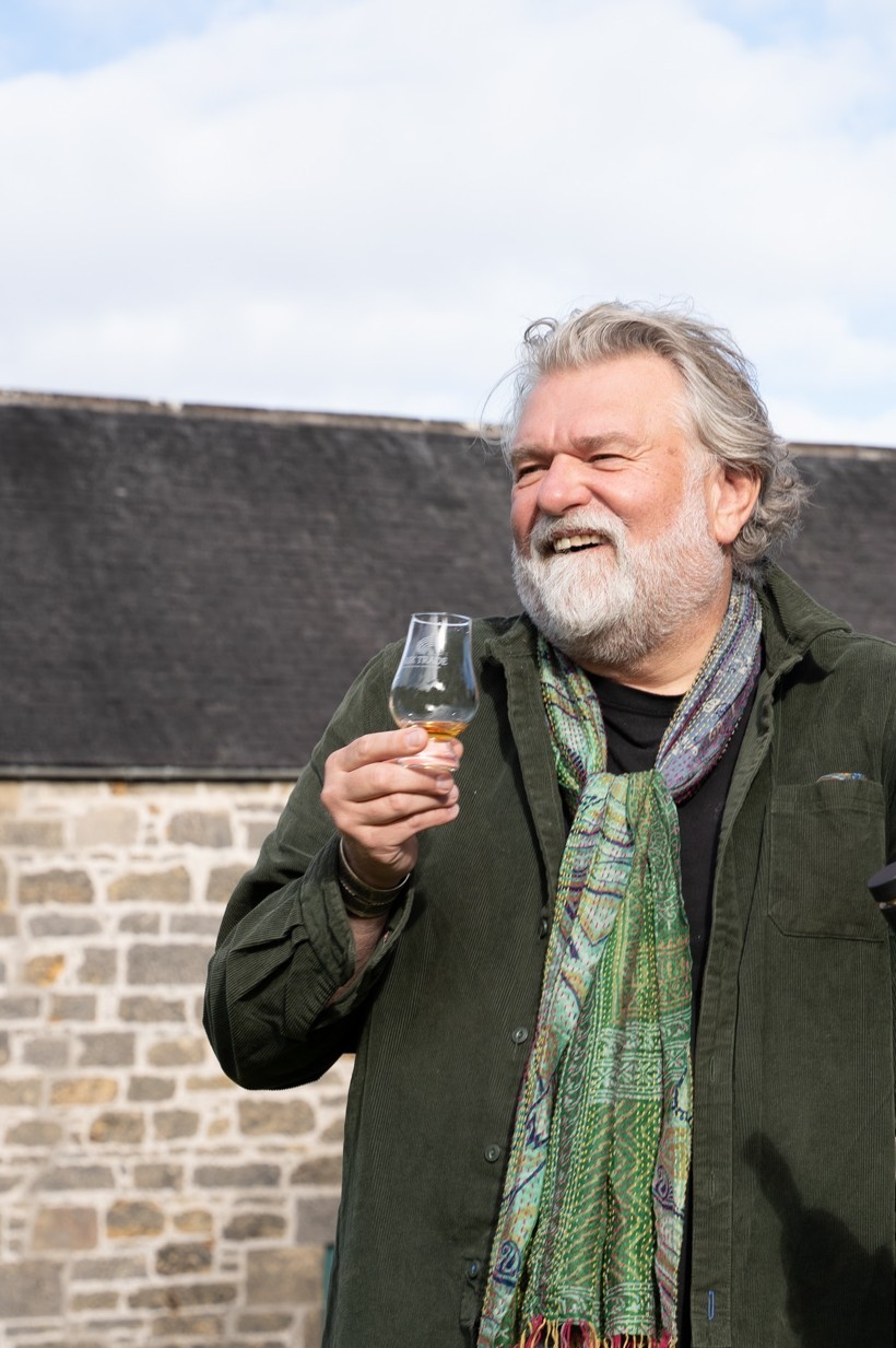 Si King holding a glass with a small amount (or dram) of whisky in it, laughing, because who isn't having a nice time when drinking fine whiskies