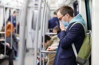 masked man coughing on the subway