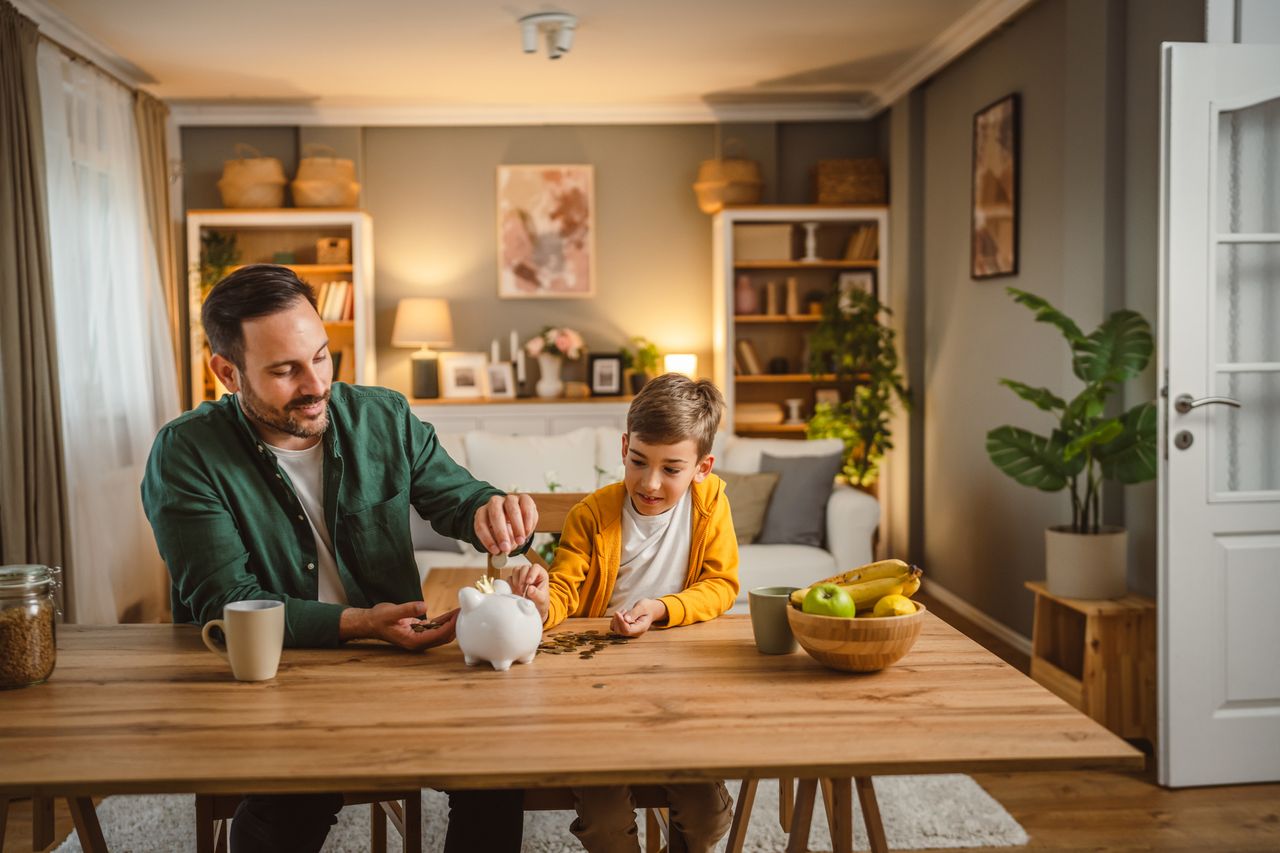 Father and son putting savings into a piggy bank