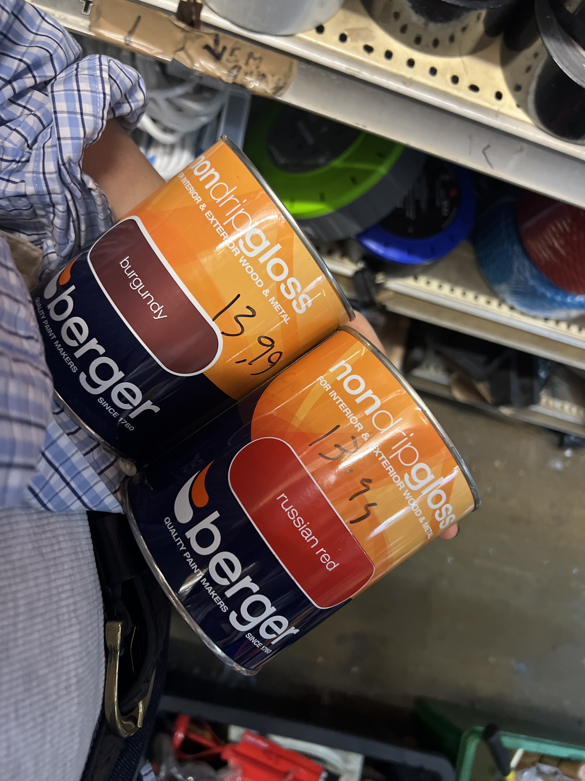 Image of someone holding two paint cans in what seems to be a hardware aisle
