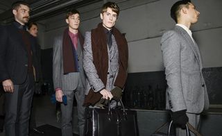 Male model posing and holding briefcases