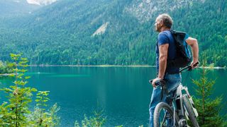Man leaning on e-bike looking out across lake