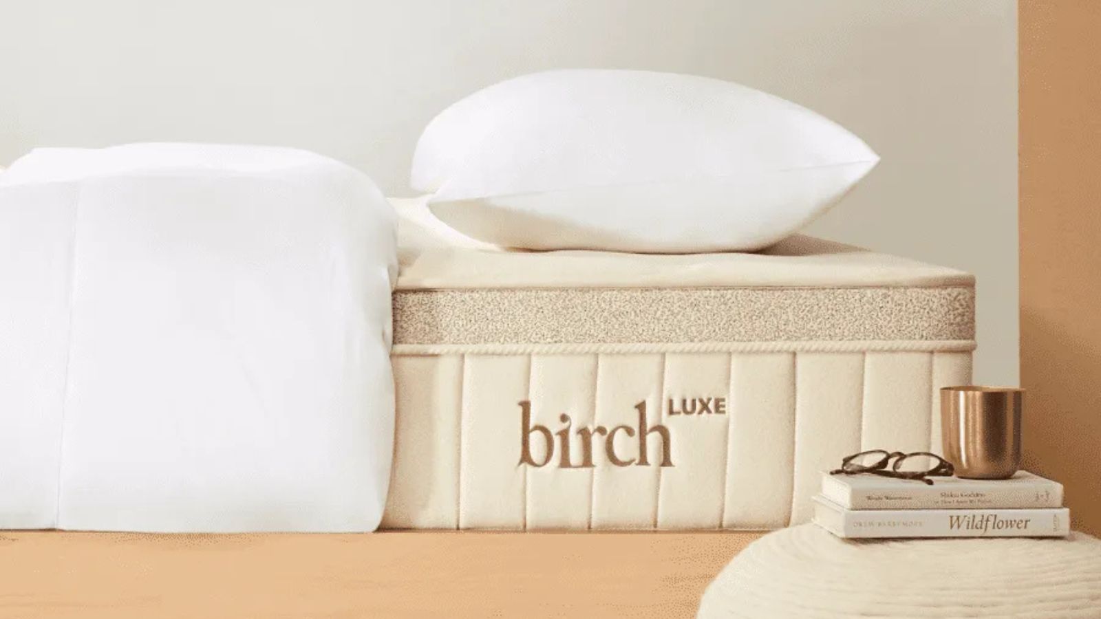Bedding and pillow on the Birch mattress topper against a white wall. 