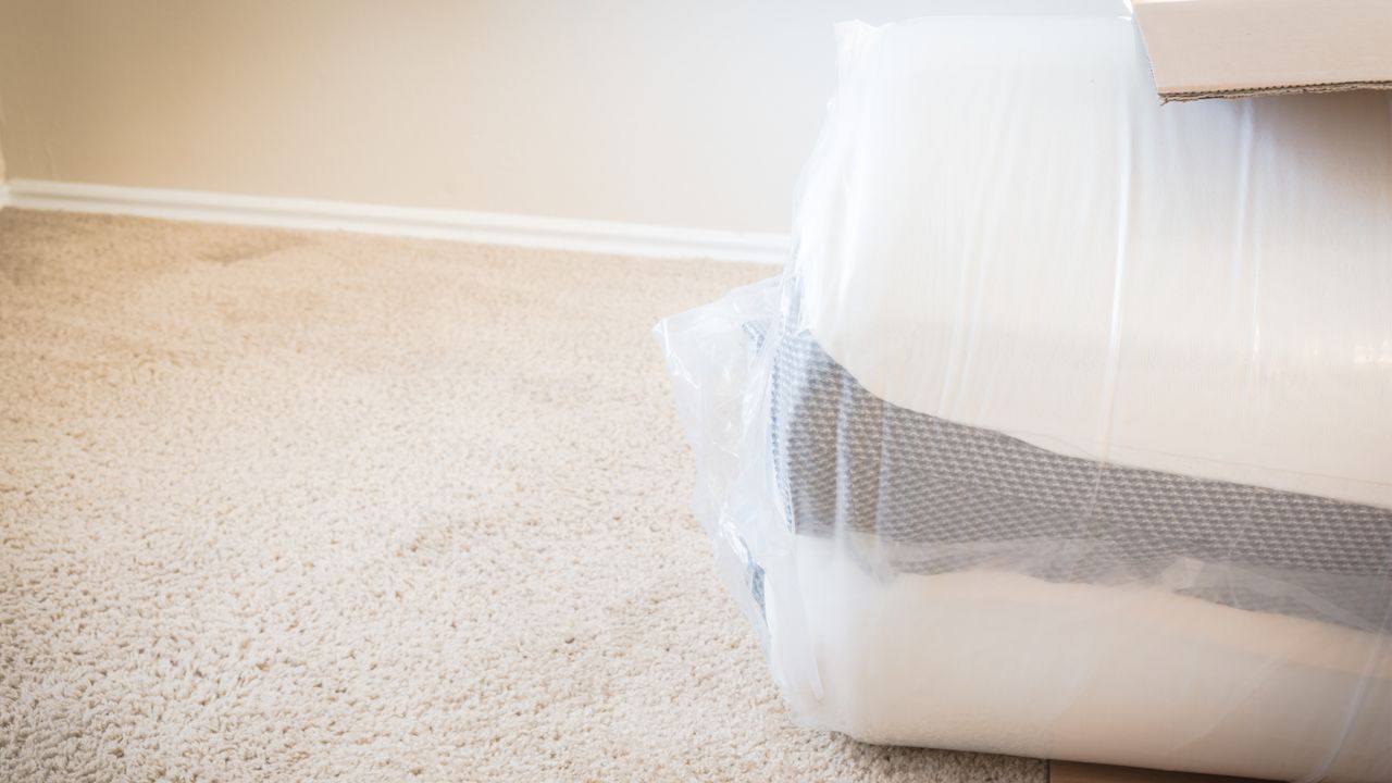 Close-up top view roll-packed spring mattresses in mattress bags on carpet floor background