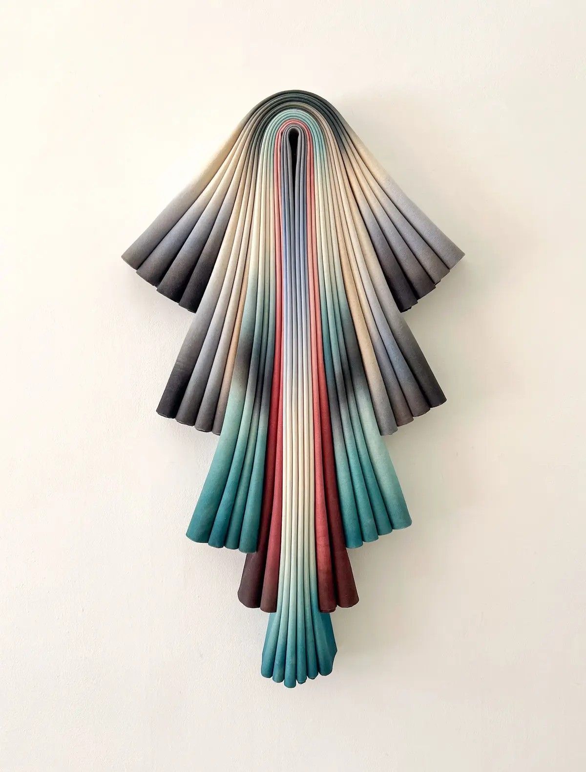 A textile sculpture made from different, cangiant fragments of fabrics draped together in an upside-down tree-like shape.
