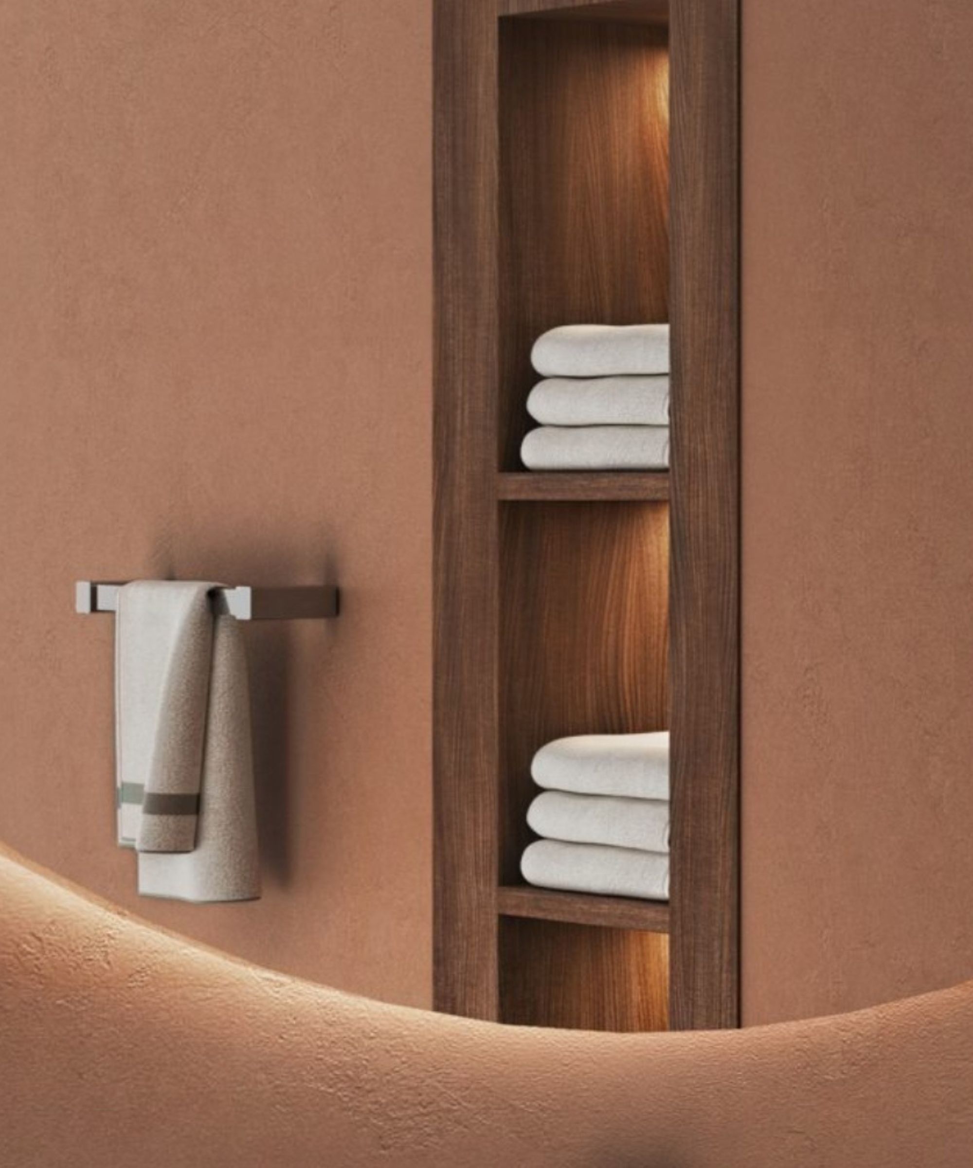 Built-in wooden niches with subtle lighting showcase neatly folded towels. A simple wall-mounted rail keeps a hand towel within easy reach against warm, textured plaster walls.