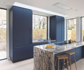 blue cabinetry in kitchen with pink veined marble counter top