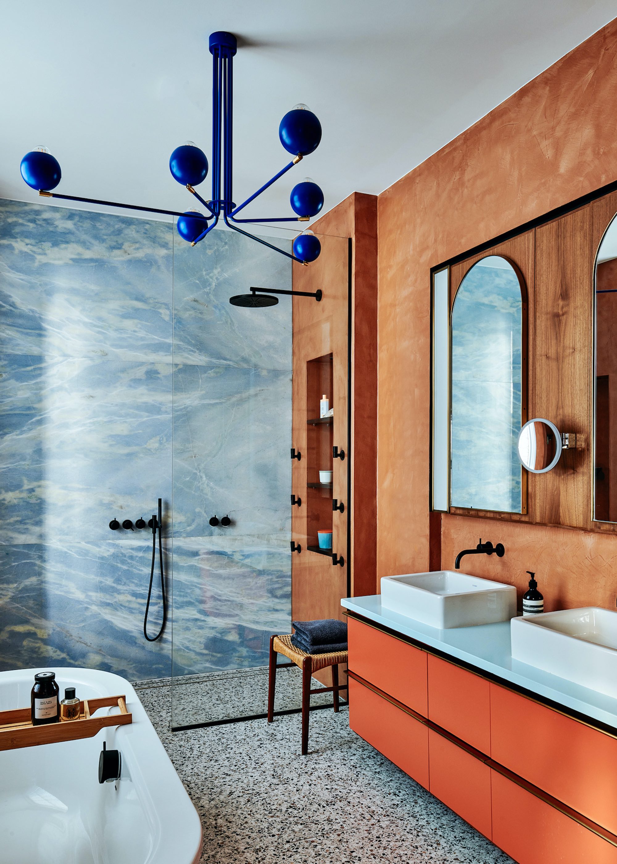 bathroom with orange vanity and terrazzo flooring and blue shower wall