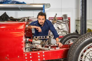 Richard Hammond wearing overalls and fixing a red classic car in Richard Hammond&#039;s Workshop. 