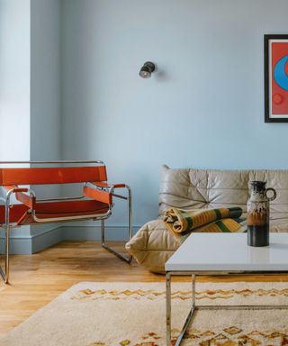 living room with light blue walls, beige soft, red accent chair, white coffee table