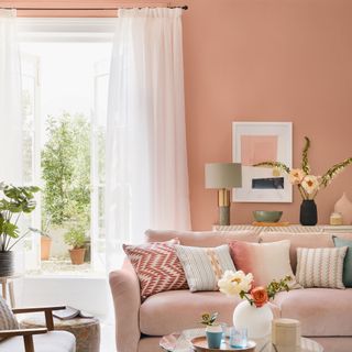 pink living room with sofa, side table and white curtains