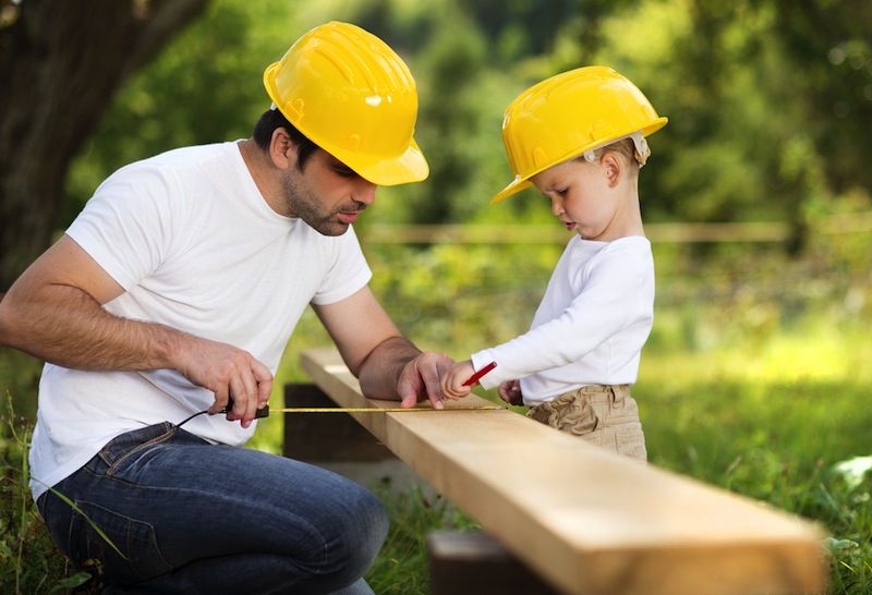 A little boy helps his dad measure lumber.