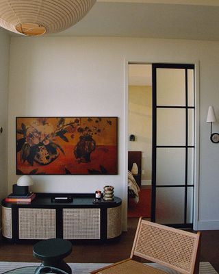 living room with rattan entertainment unit, rattan chair, artwork TV, and paper lantern