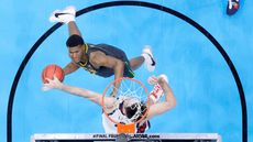 Two basketball players face off under the rim.