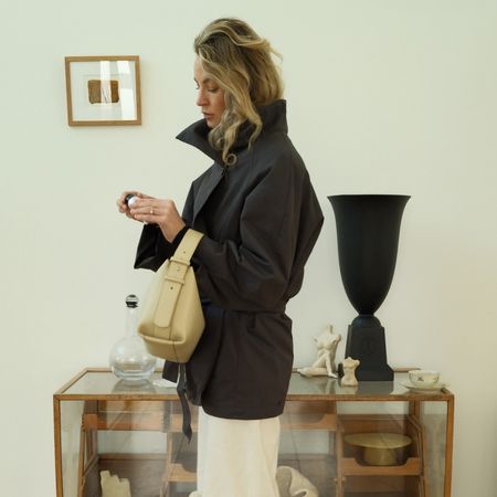 Anouk Vye wears a black leather jacket, white trousers and a yellow handbag.