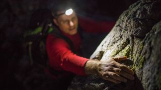 Rock climber finds a hand hold while climbing at night