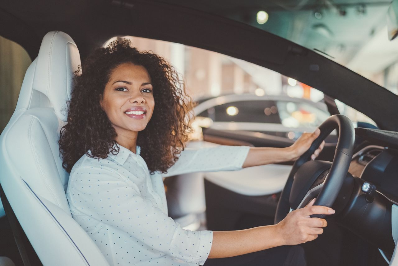 Woman sitting in a luxury car at a dealership