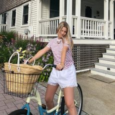 A girl wearing a striped t shirt riding a bike with a wicker basket