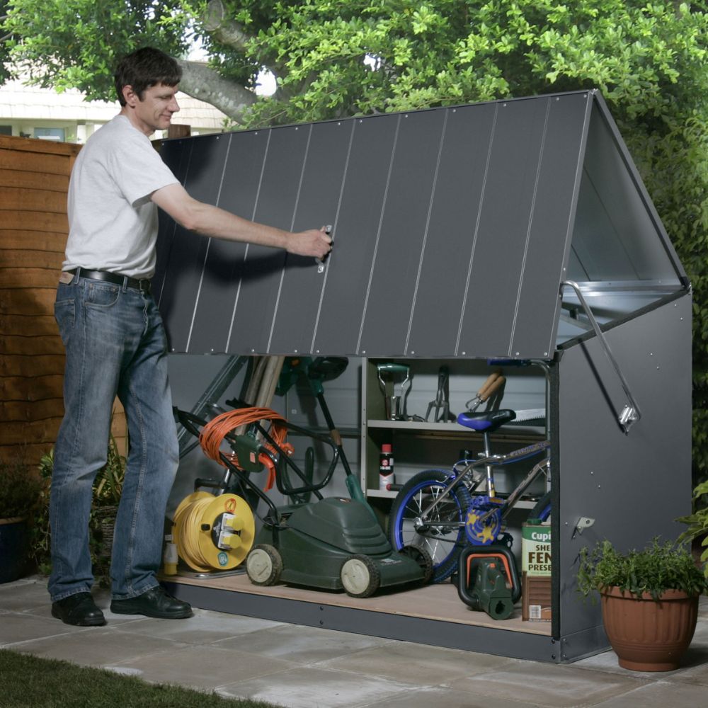 Man opening a sleek grey metal garden storage unit filled with tools, a lawnmower and outdoor equipment. The sturdy, weatherproof shed features a lift-up lid with gas struts, ideal for secure, space-saving garden storage on a patio or in a small garden.