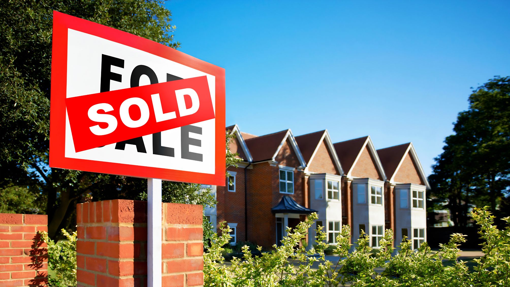 A home for sale sign with a SOLD sticker over it. 