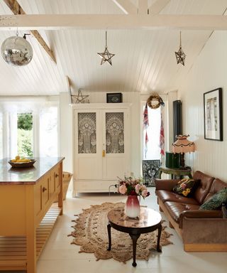 white kitchen with yellow kitchen island and vintage brown leather couch