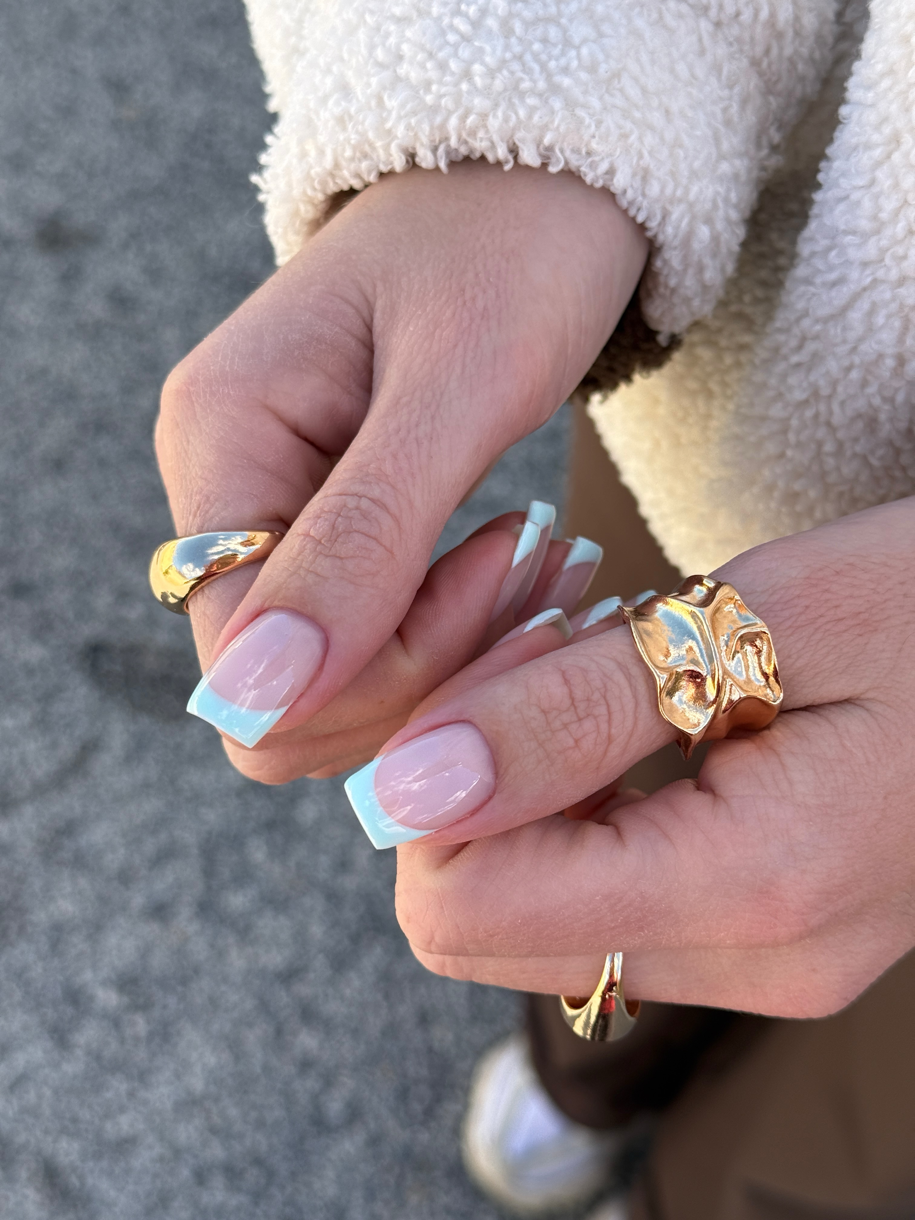 Square nails with a sheer pink base and aquamarine French tips