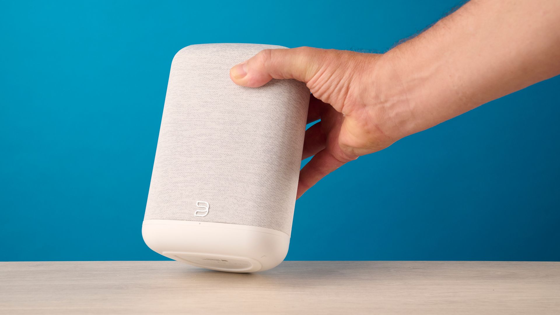 the bluesound pulse flex wi-fi speaker in pale gray photographed against the blue tom's guide background