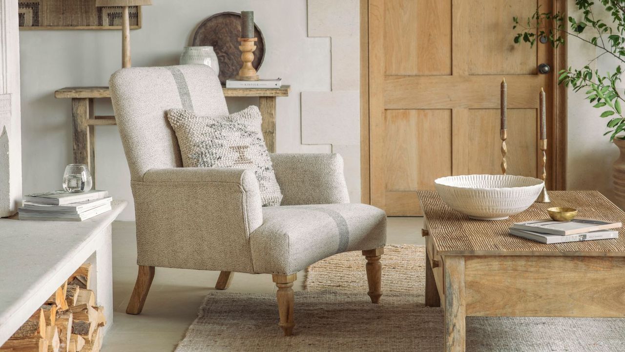 A neutral living room with a cream armchair in front of a low wooden coffee table