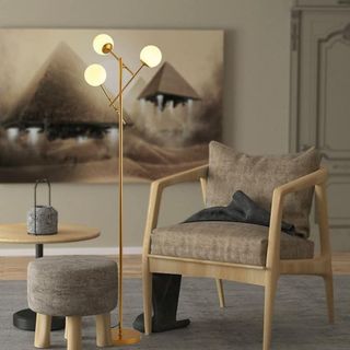 A tall sculptural gold floor lamp next to an armchair