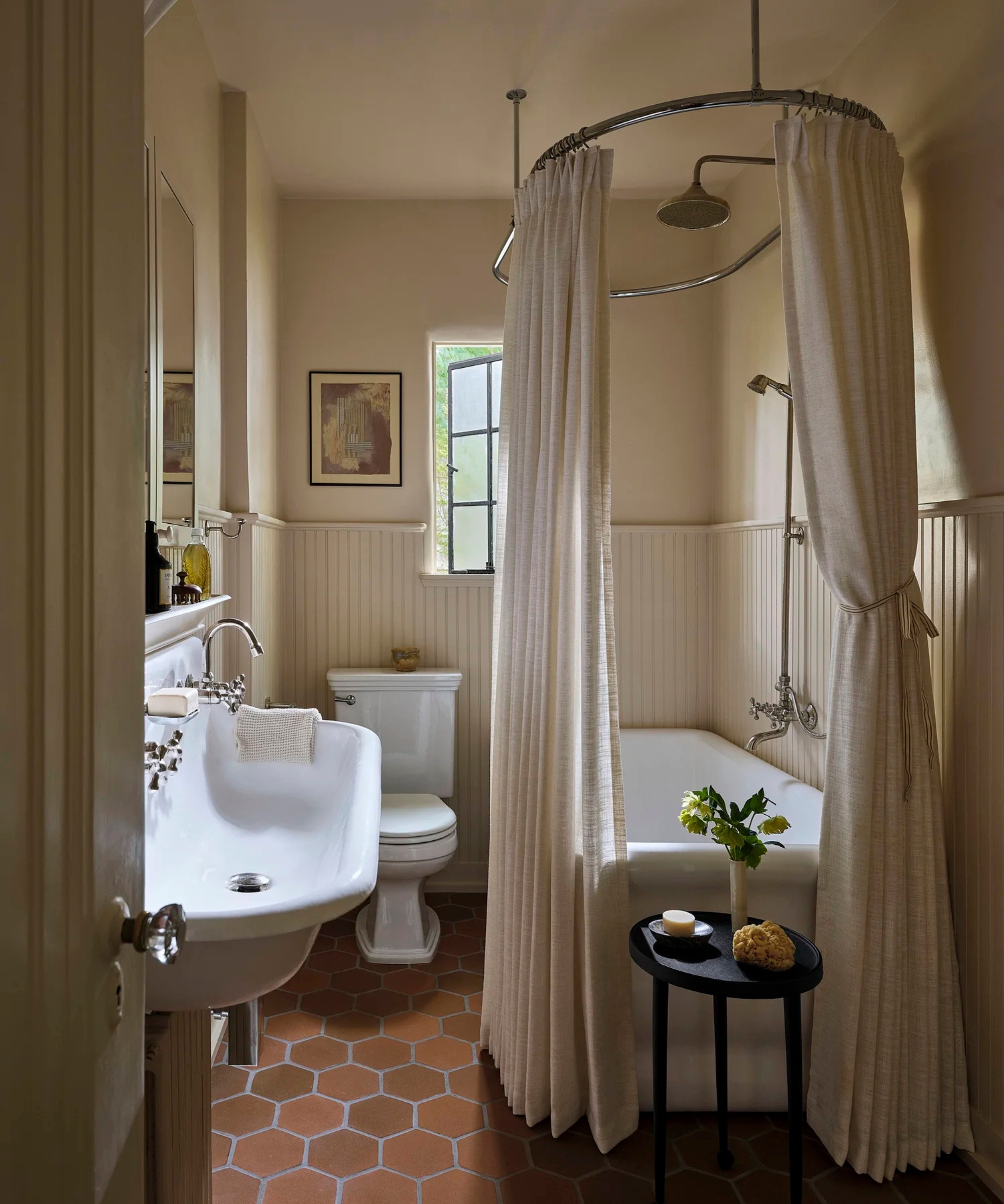 A small bathroom color drenched in a warm neutral hue, paired with hexagonal terracotta floor tiles