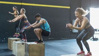 Group of people perform box jumps in the gym