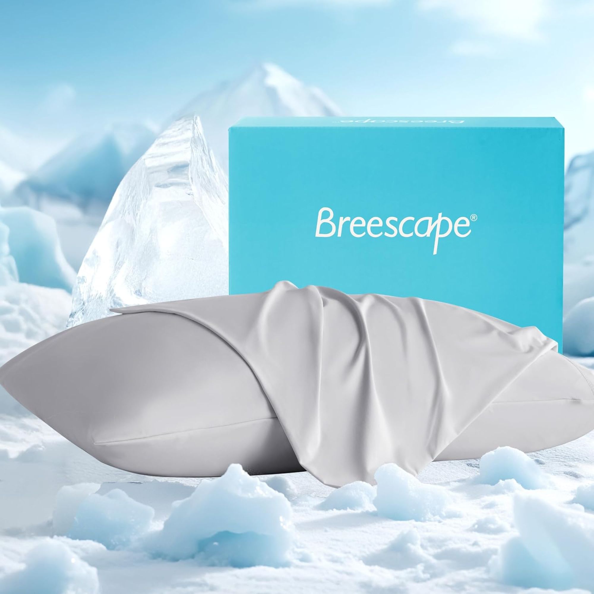 A grey Breescape cooling pillowcase shown on a pillow in a cloud landscape with a blue packaging box behind.