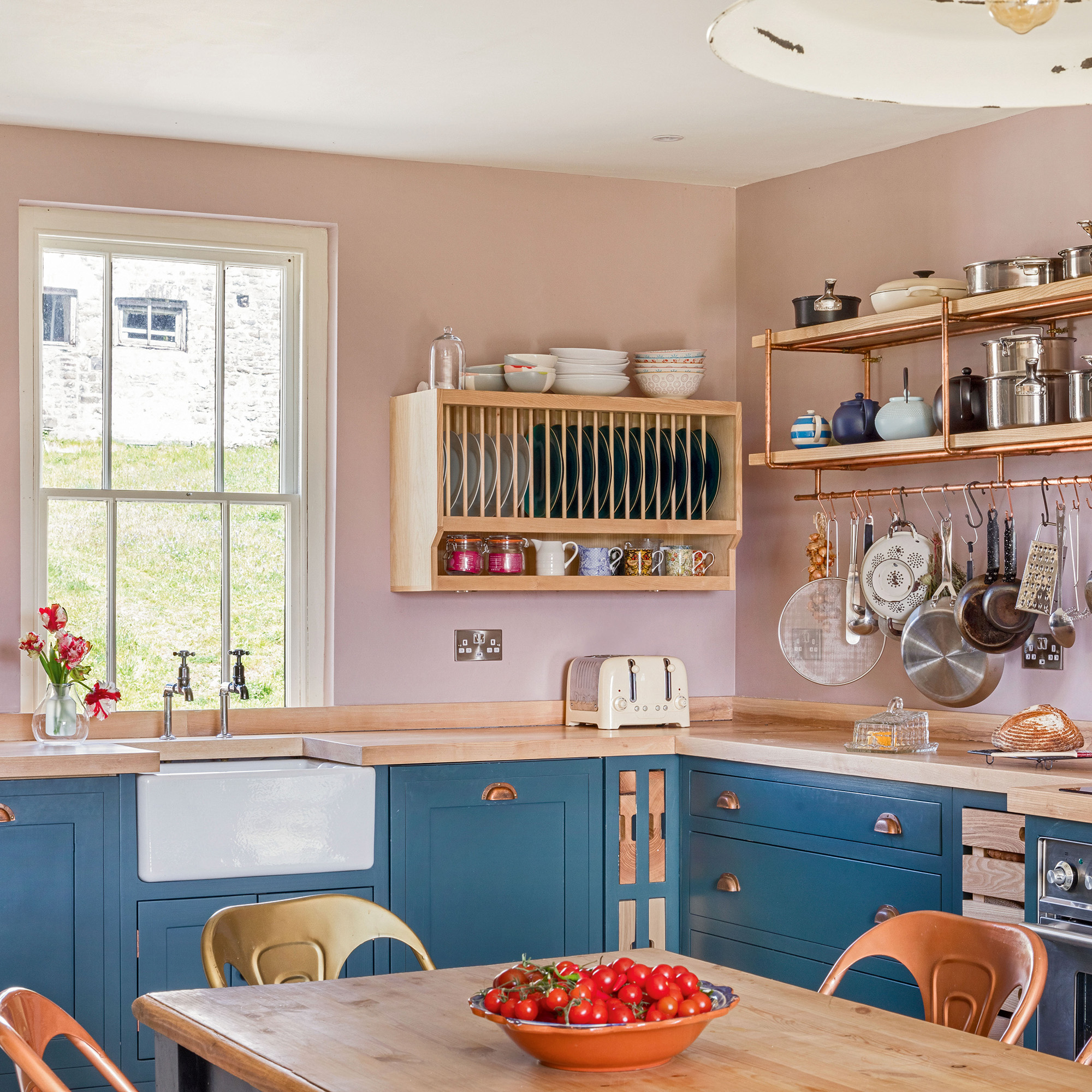 country kitchen with pink wall and blue cabinetry and white butler's sink and ash plate rack and open shelves