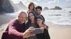 A man taking a selfie with his family on the beach. 