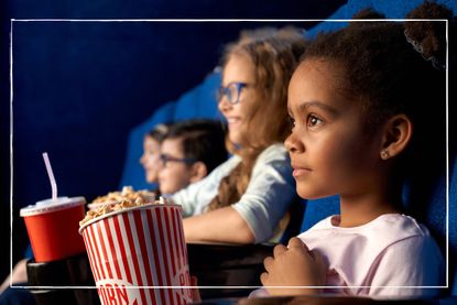 Kids with popcorn sat in blue seats in a cinema screening room